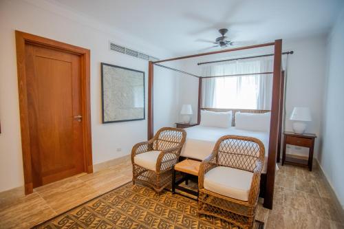 a bedroom with a canopy bed and two chairs at Xeliter Balcones del Atlantico - Las Terrenas in Las Terrenas