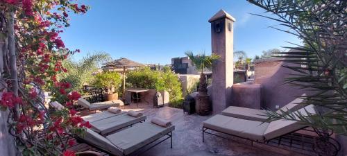 une terrasse avec des canapés et des fleurs et une tour d'horloge dans l'établissement Dar Darma, à Marrakech