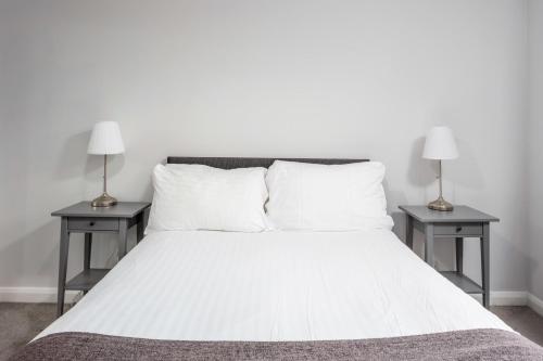a white bed with two nightstands and two lamps at Prestwick Central - Donnini Apartments in Prestwick