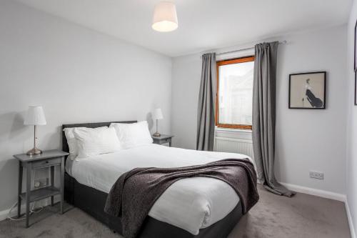 a white bedroom with a bed and a window at Prestwick Central - Donnini Apartments in Prestwick