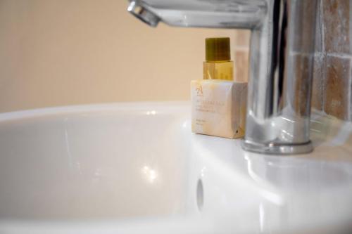 a bottle of oil sitting on a bathroom sink at Prestwick Central - Donnini Apartments in Prestwick