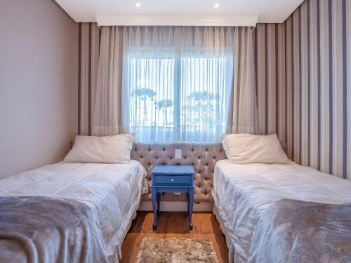 1 dormitorio con 2 camas y ventana en Vivendas da Montanha 102 - Apto em Gramado junto ao Hotel Colline de France, en Gramado