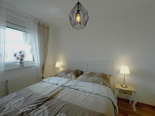 a bedroom with a bed and a chandelier and a window at Orhidea Doboj in Doboj