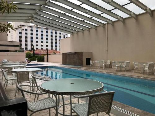 a pool with tables and chairs next to a building at Flat Nobile Congonhas em frente ao aeroporto - H614 in São Paulo