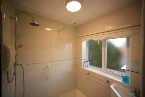 ein Badezimmer mit Dusche und Waschbecken und einem Fenster in der Unterkunft A beautiful 3-bed Family House in Ormskirk, sleeps 5 in Ormskirk
