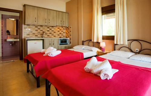 a room with three beds with red sheets at Livari Studios in Vourvourou