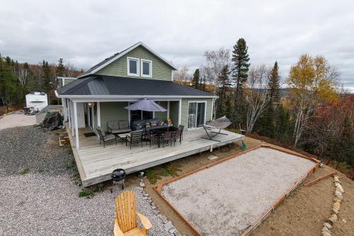 a house with a deck with a table and chairs at Le Saint Placide de Charlevoix in Baie-Saint-Paul