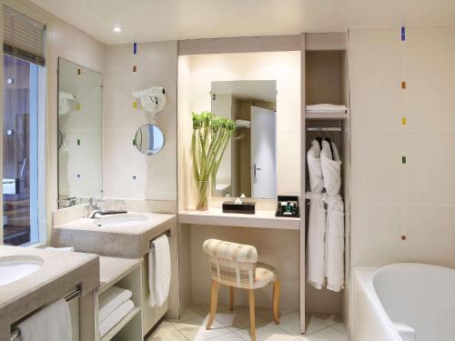 a bathroom with a sink and a tub and a toilet at Sofitel Golfe d'Ajaccio Thalassa Sea & Spa in Ajaccio
