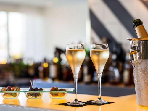 two glasses of champagne on a table with a plate of food at Sofitel Golfe d'Ajaccio Thalassa Sea & Spa in Ajaccio