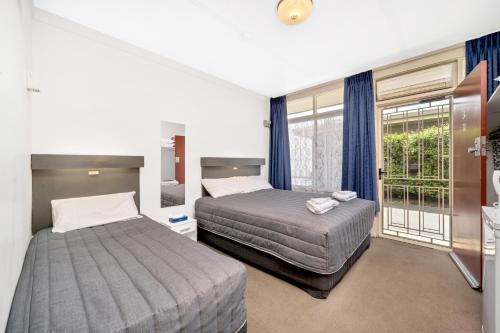 a hotel room with two beds and a balcony at Central Wangaratta Motel in Wangaratta