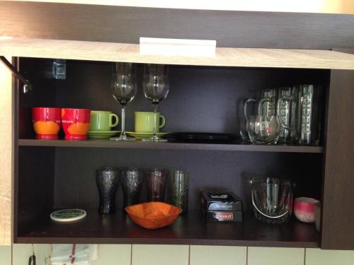 a shelf with cups and wine glasses on it at Nexus Studio Deluxe in Miercurea-Ciuc