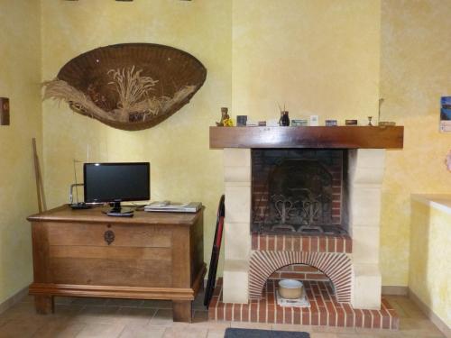 un soggiorno con camino e TV su scrivania di Les Baillis a Villegenon