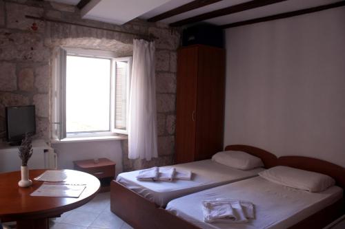 a bedroom with two beds and a table and a window at Apartment Biline Center in Korčula