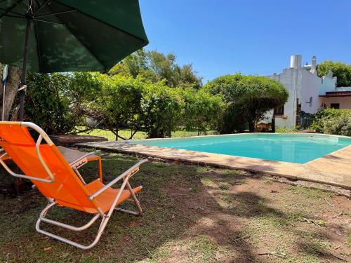 una silla y una sombrilla junto a la piscina en Casa Bellavista en Villa Lía