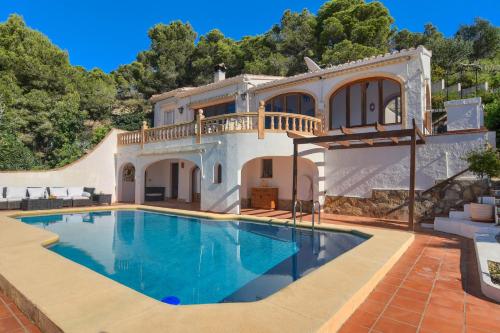 a villa with a swimming pool in front of a house at Casa Patricia in Jávea