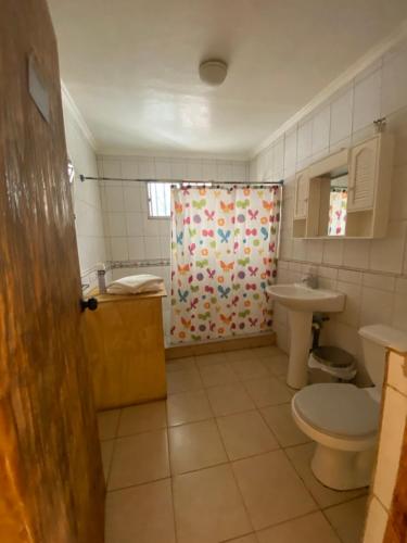 a bathroom with a shower curtain and a toilet at Casa grande Campestre, Vicuña, Valle del Elqui in Vicuña