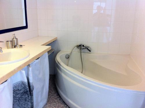 une salle de bain blanche avec une baignoire et un lavabo dans l'établissement Les Argonautes, à Villeneuve-Loubet
