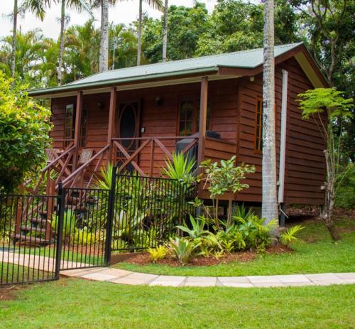 a wooden house with a fence in front of it at Sunshine Valley Cottages in Woombye
