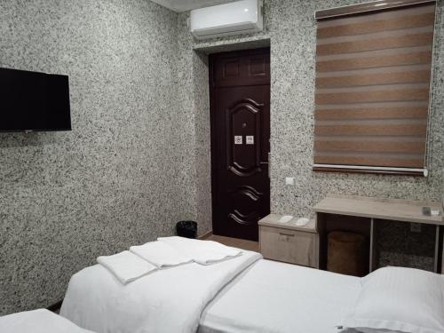 a bedroom with two beds and a tv and a door at Taxtapul Hotel in Tashkent