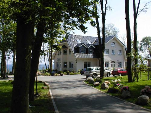 a large white house with cars parked in front of it at Waldpavillon in Fehmarn