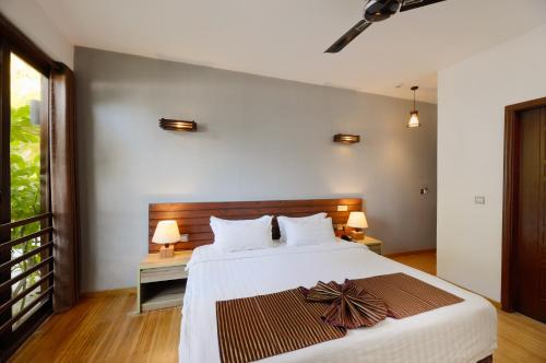 a bedroom with a large white bed with a wooden headboard at Aveyla Manta Village in Dharavandhoo