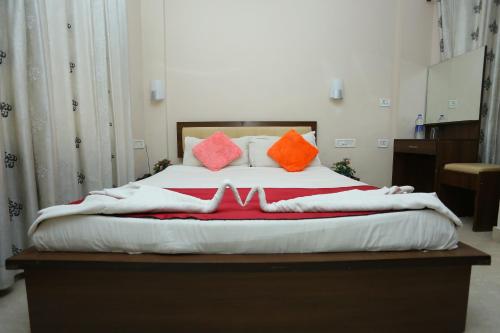 a large bed with red and orange pillows on it at Hotel Innate Inn in Alwaye