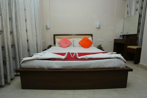 a bed with orange and orange pillows on it at Hotel Innate Inn in Alwaye