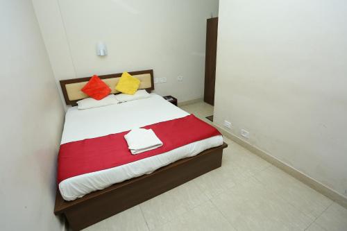 a bedroom with a bed with red and yellow pillows at Hotel Innate Inn in Alwaye