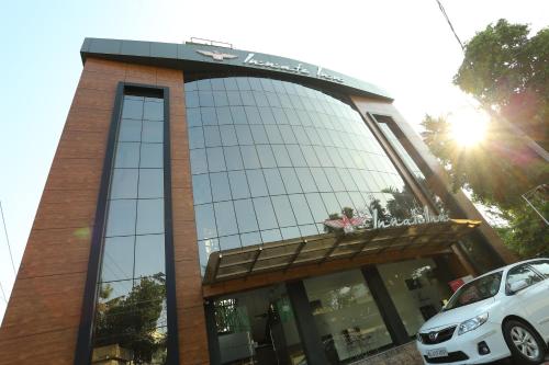 a building with a car parked in front of it at Hotel Innate Inn in Alwaye