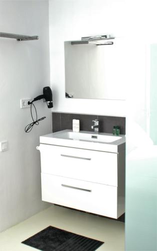 a bathroom with a white sink and a mirror at JINGTU Wellness & Spa B&B in Comares
