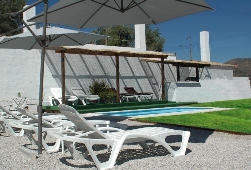 a group of chairs and an umbrella next to a pool at JINGTU Wellness & Spa B&B in Comares