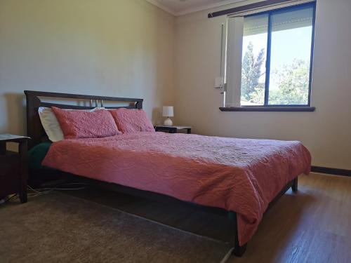 a bedroom with a bed with a red comforter and a window at Maggie's Family Retreat in Rockingham