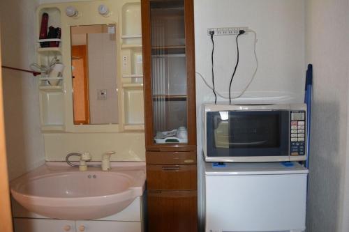 een kleine badkamer met een magnetron en een wastafel bij Amakusa - House / Vacation STAY 5358 in Amakusa