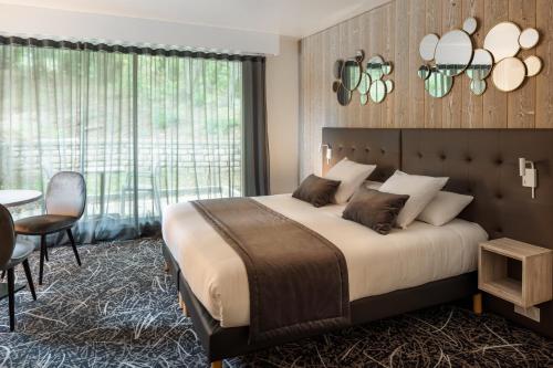 1 dormitorio con 1 cama grande, mesa y sillas en Logis Hôtel Parenthèse, Restaurant & Spa en Chille