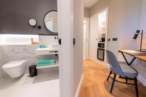 a bathroom with a toilet and a desk and a chair at L&H Gran Vía Valencia in Valencia