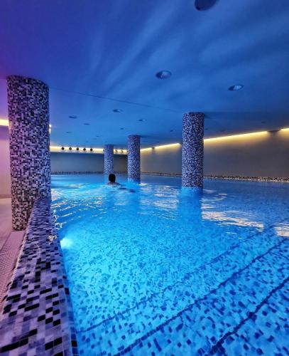 a swimming pool in a building with blue water at Apartman DreamHome in Vrnjačka Banja