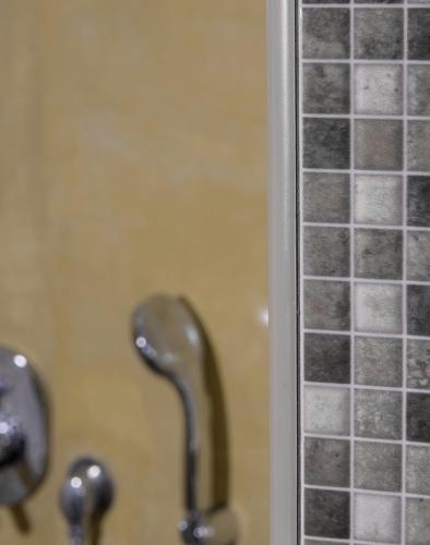 a shower stall with glass tiles on the wall at Hotel Sunrise in Fira