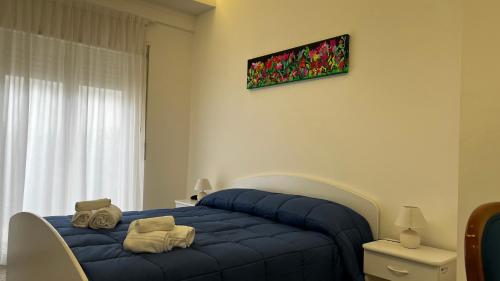 un letto blu in una stanza con un dipinto sul muro di Al Saliceto Hotel a Patti