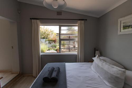 una camera con un letto e due paia di pantofole sopra di Surf Way Beach cottage a Città del Capo