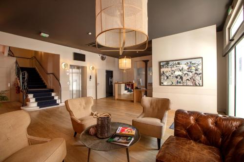 a living room with a couch and chairs and a table at Hôtel De Paris in Sète