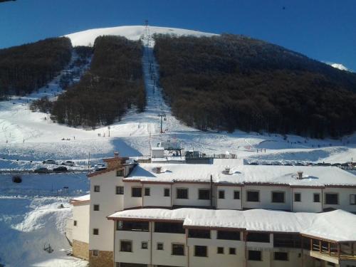 una montaña cubierta de nieve con un edificio y una pista de esquí en Monolocale Residence Paradiso Aremogna a due passi dagli impianti sciistici, en Roccaraso