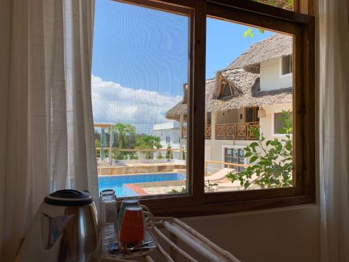 a window with a view of a swimming pool at Zanzibar Tropical Sunset Boutique Hotel - Adults Only in Kiwengwa