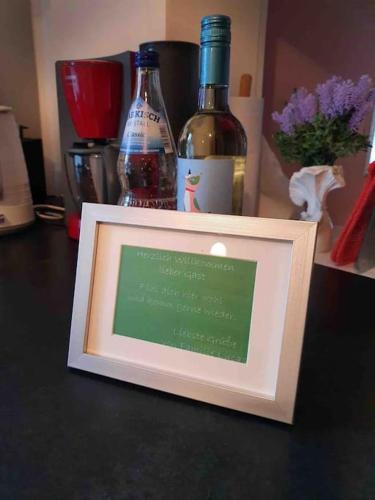 a framed picture on a table with bottles of wine at Alexandrowka Wohnen im UNESCO Weltkulturerbe Haus in Potsdam