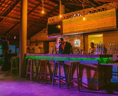 a bar with stools at a bar with people sitting at it at Pousada ON VIBE Cumbuco in Cumbuco