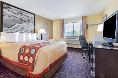 a hotel room with a bed and a flat screen tv at Super 8 by Wyndham Decorah in Decorah