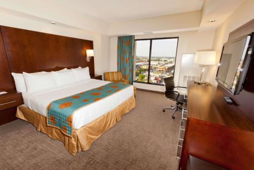 オーランドにあるRamada Plaza by Wyndham Orlando Resort & Suites Intl Driveのベッド、デスク、テレビが備わるホテルルームです。