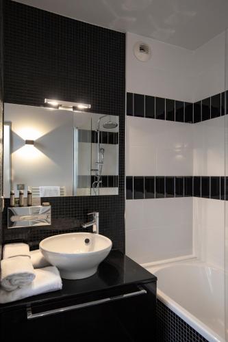 a black and white bathroom with a sink and a tub at Hôtel De Paris in Sète