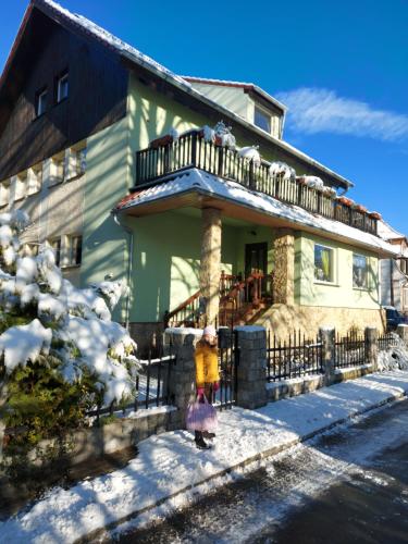 Una chica parada frente a una casa en la nieve en Villa Veronika, en Lądek-Zdrój