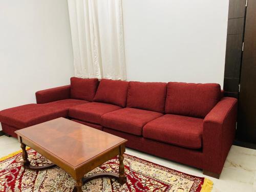a red couch in a living room with a coffee table at Alhama Hotel Appartment in Khasab