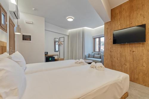 a bedroom with a large white bed with a flat screen tv at Harma Boutique Hotel in Hersonissos